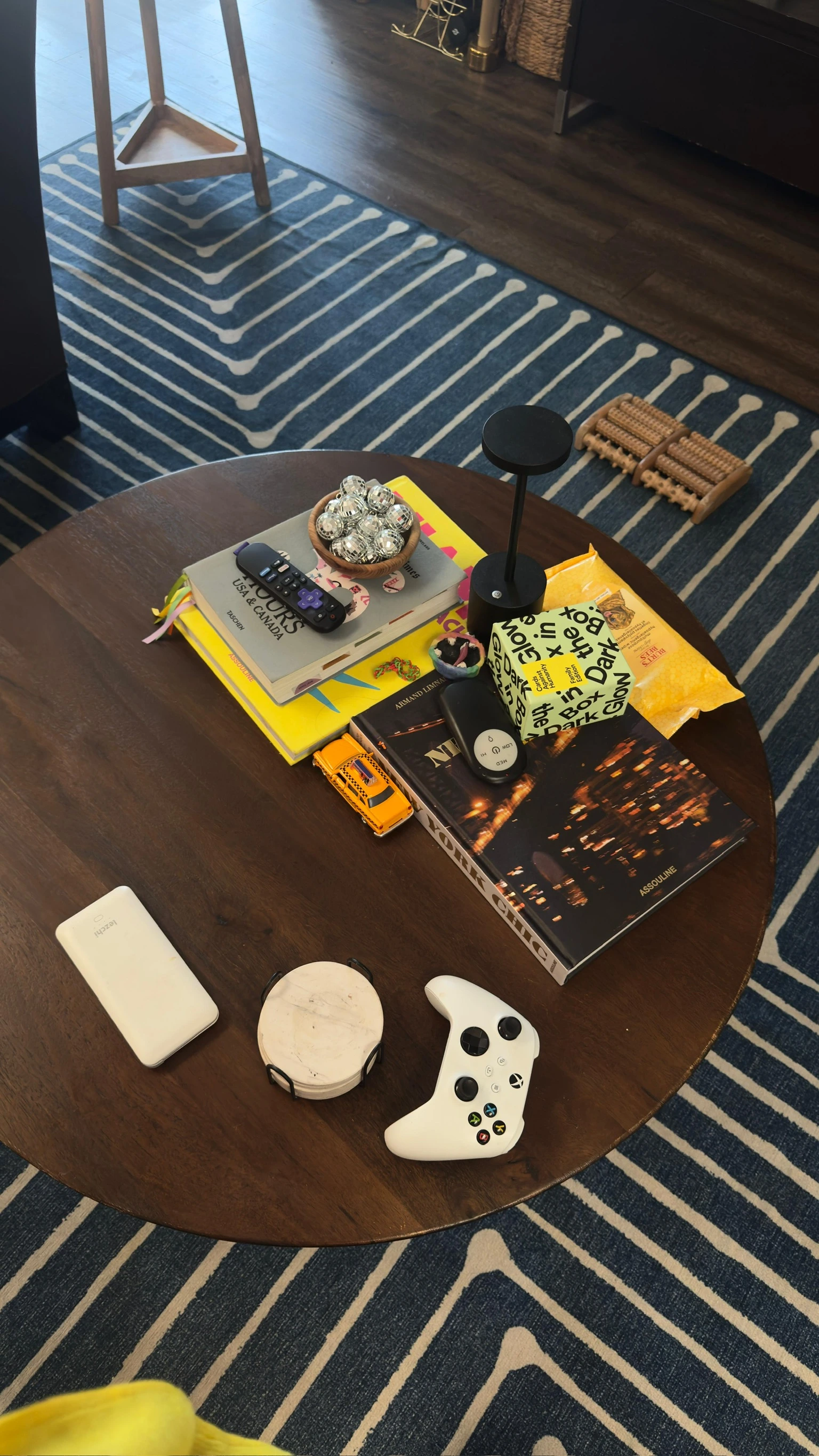 Arranged table with magazines, books, a video game controller, and a bag